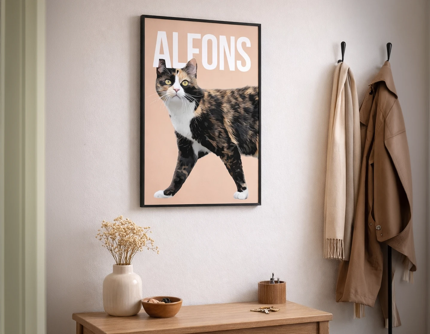 Katten Alfons i en modern tavla, snyggt typografiskt designad. Kattens namn är skriven högst upp på tavlan i stora bokstäver och är delvis framför och bakom öronen på katten. Tavlan hänger i en hall på väggen i svart träram.