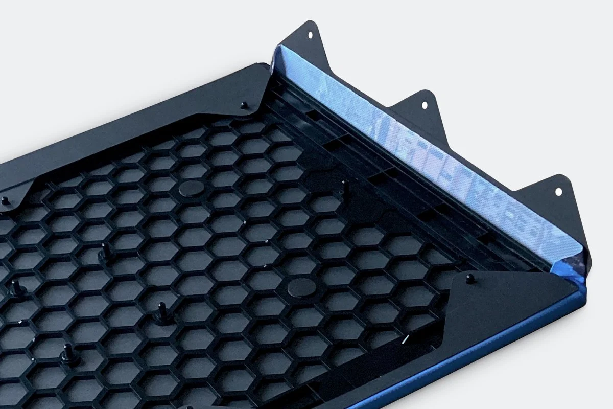 Instruktionsbild hur en front appliceras på en IKEA Symfonisk-högtalare. Trycket är på en duk med flärpar och hål, som enkelt fästs på frontens baksida.